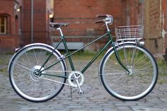 a green bicycle parked on the side of a brick road next to an old building