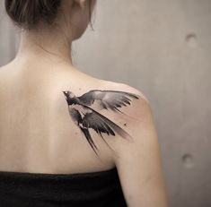 a woman with a black and white tattoo on her upper back shoulder, flying bird