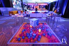 a glass table with candles and balls on it in a room filled with tables and chairs