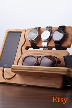 three watches and two cell phones in a wooden display case on a table with an iphone