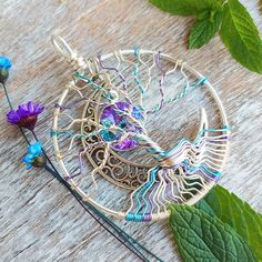 a piece of metal wire with flowers and leaves around it on top of a wooden table