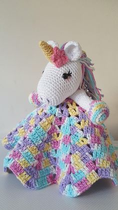 a crocheted unicorn sitting on top of a blanket