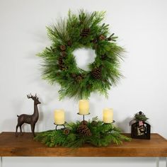 a table topped with a wreath and candles next to a deer figurine on top of it