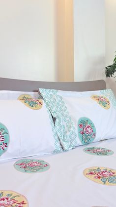 a bed with white sheets and pillows on top of it next to a potted plant