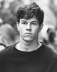 black and white photograph of a young man looking at the camera with people in the background