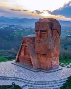 an artistic sculpture in the shape of a face on top of a stone platform with steps leading up to it