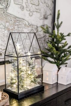 a small christmas tree in a glass case on top of a table next to other decorations