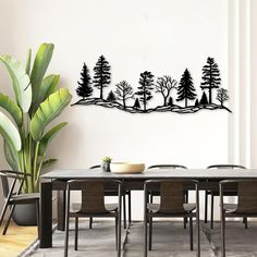 a dining room with a table and chairs in front of a wall that has trees on it