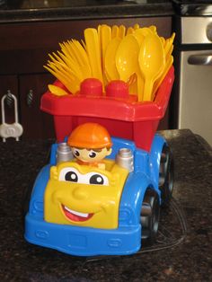 a toy truck with plastic forks and spoons in it on a kitchen counter top