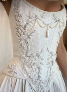 the back of a white wedding dress with beading and pearls on it's waist