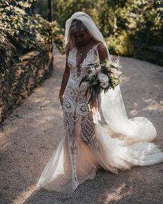 a woman in a wedding dress walking down a path