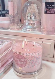 a pink party candle sitting on top of a counter next to other items in front of a mirror