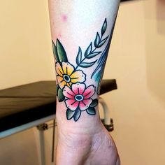 a person with a flower tattoo on their left arm and wrist is holding onto a chair