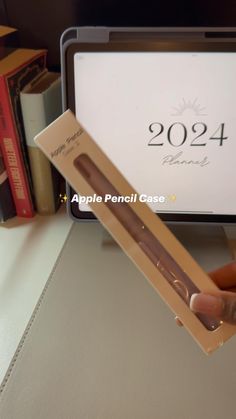 a person holding an apple pencil in front of a computer screen with the logo on it