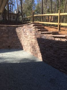 some bricks are stacked on top of each other in front of a fence and trees