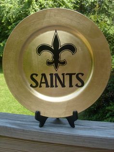 a new orleans saints glass plate sitting on top of a wooden table in front of some trees