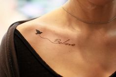 a woman with a tattoo on her chest that says believe and a bird flying in the sky