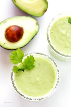 two glasses filled with avocado smoothie and garnished with cilantro