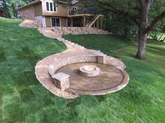 an outdoor fire pit in the middle of a grassy area with stairs leading up to it