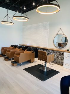 a hair salon with lots of chairs and mirrors on the wall, lights hanging from the ceiling