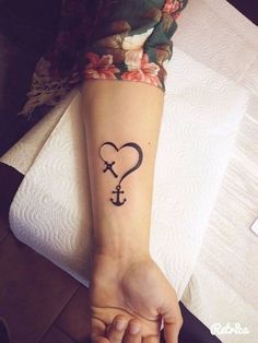 a woman's arm with an anchor and heart tattoo on her left wrist, which is in the shape of a heart