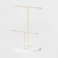 a pair of gold - plated metal clothes stands on a white pedestal, with two bars in the middle