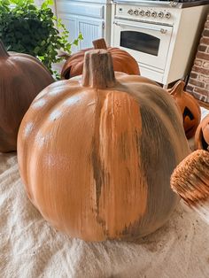 three pumpkins sitting on top of a table next to a oven and potted plant