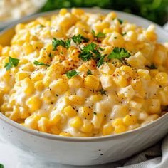 a white bowl filled with corn and garnished with parsley on the side