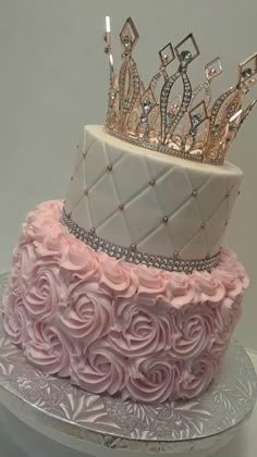 a three tiered cake decorated with pink roses and a tiara on the top