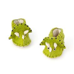 a pair of green slippers with black eyes and horns on them, sitting next to each other