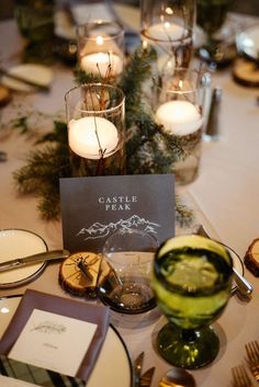 the table is set with candles, plates and menus for an elegant dinner party