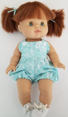 a doll with red hair wearing a blue dress and white tennis shoes is laying on the floor