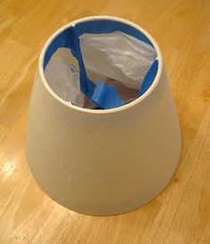 a lamp shade with plastic bags in it on a wood flooring surface, showing the bottom part of the light fixture