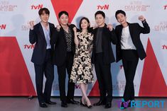 four people posing for a photo in front of a red and white wall with the words tvn written on it