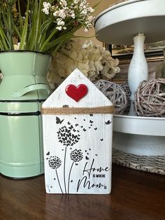 a wooden house with a red heart on the roof and flowers in vases next to it