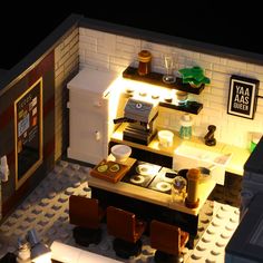 a lego model of a small kitchen and dining area with lights on the counter top