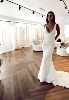 a woman in a white dress is standing on a wooden floor and looking at the camera