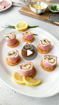 small appetizers are arranged on a plate with lemon wedges and garnishes