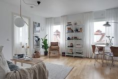 a living room filled with lots of furniture next to a white table and bookshelf