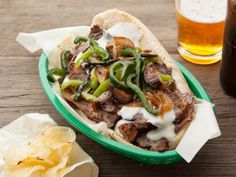 a green plate topped with meat and veggies next to a glass of beer