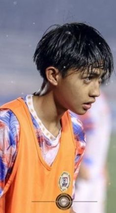 a young man wearing an orange vest on a soccer field