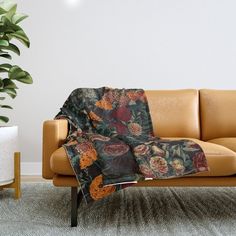 a couch with a blanket on it next to a potted plant