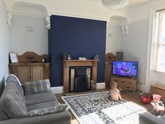 a baby sitting on the floor in front of a tv and fireplace with blue walls