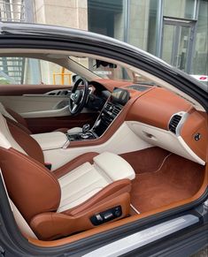 the interior of a car is shown in brown and white leather, with its door open