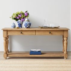 a wooden table with two vases on it and a blue and white flower arrangement