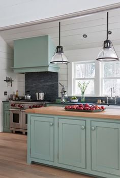 a kitchen with green cabinets and an island in front of the stove, sink and oven