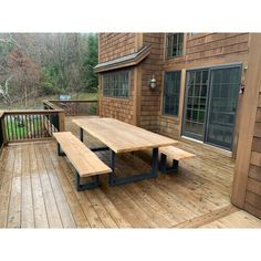 a picnic table sitting on top of a wooden deck next to a building with windows