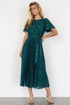 Step into sophistication with the Mindy Pleated Dress in deep emerald green. Faux applique florals, bloused bodice, flutter sleeves, and ankle-length pleated skirt ensure timeless elegance, with a natural waist, detachable sash, and full lining for comfort. Green Chiffon Midi Dress For Formal Occasions, Green Chiffon Midi Dress With Short Sleeves, Green Chiffon Short Sleeve Midi Dress, Green Short Sleeve Chiffon Midi Dress, Formal Green Chiffon Midi Dress, Formal Flowy Green Midi Dress, Lurex Dress, Tulle Midi Dress, Tulle Material