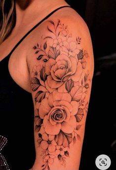 a woman's arm with flowers and leaves tattooed on the side of her shoulder