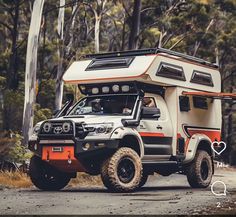 an off road camper parked on the side of a road with trees in the background